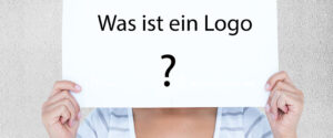 Was ist ein Logo. Frau hält Schild hoch auf dem steht Was ist ein Logo?